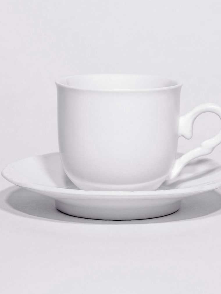 Taza blanca sobre su platillo, sobre fondo claro
