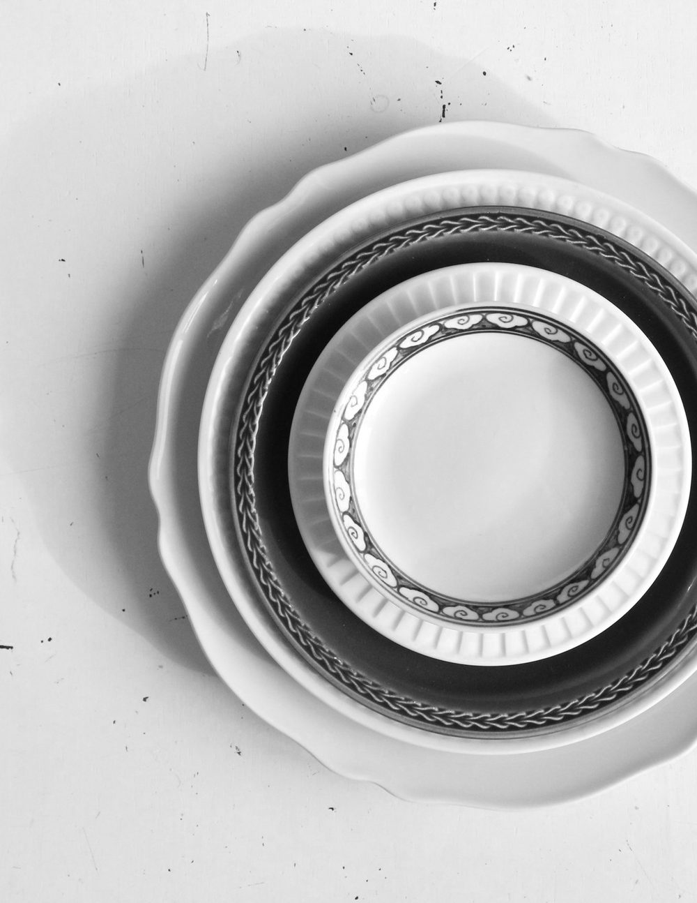 Platos blancos apilados en círculos, vistos desde arriba, en blanco y negro