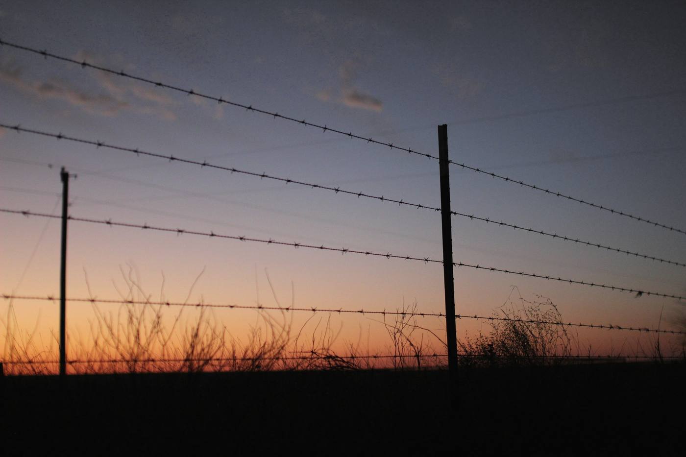 Un cerco de alambre contra un cielo violeta al anochecer