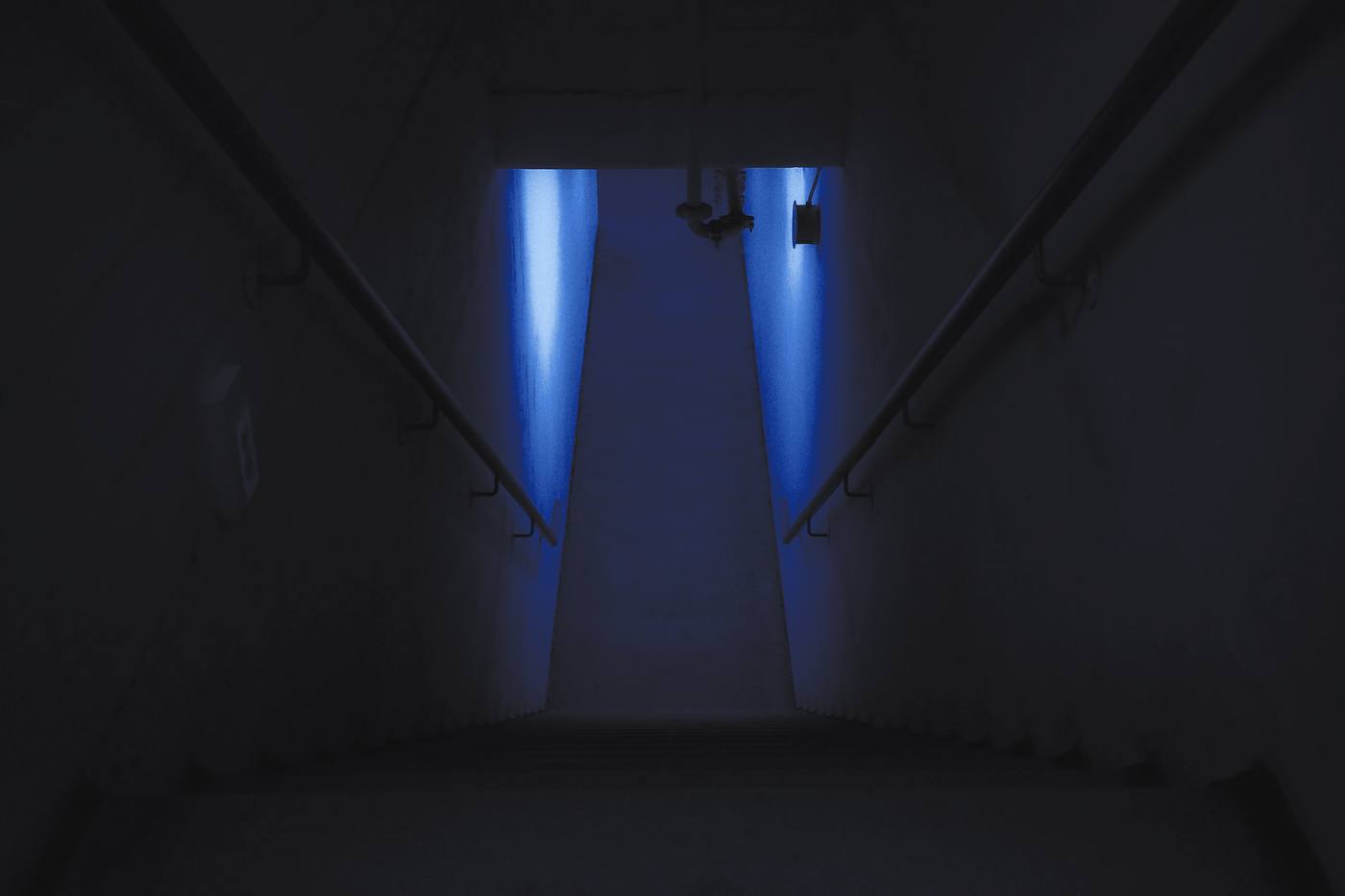 Una escalera de hormigón entre dos haces de luz, en tonos de azul