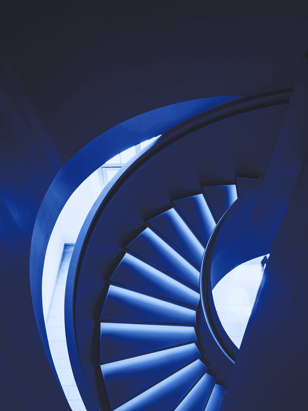 Una escalera en espiral vista desde arriba, en tonos de azul