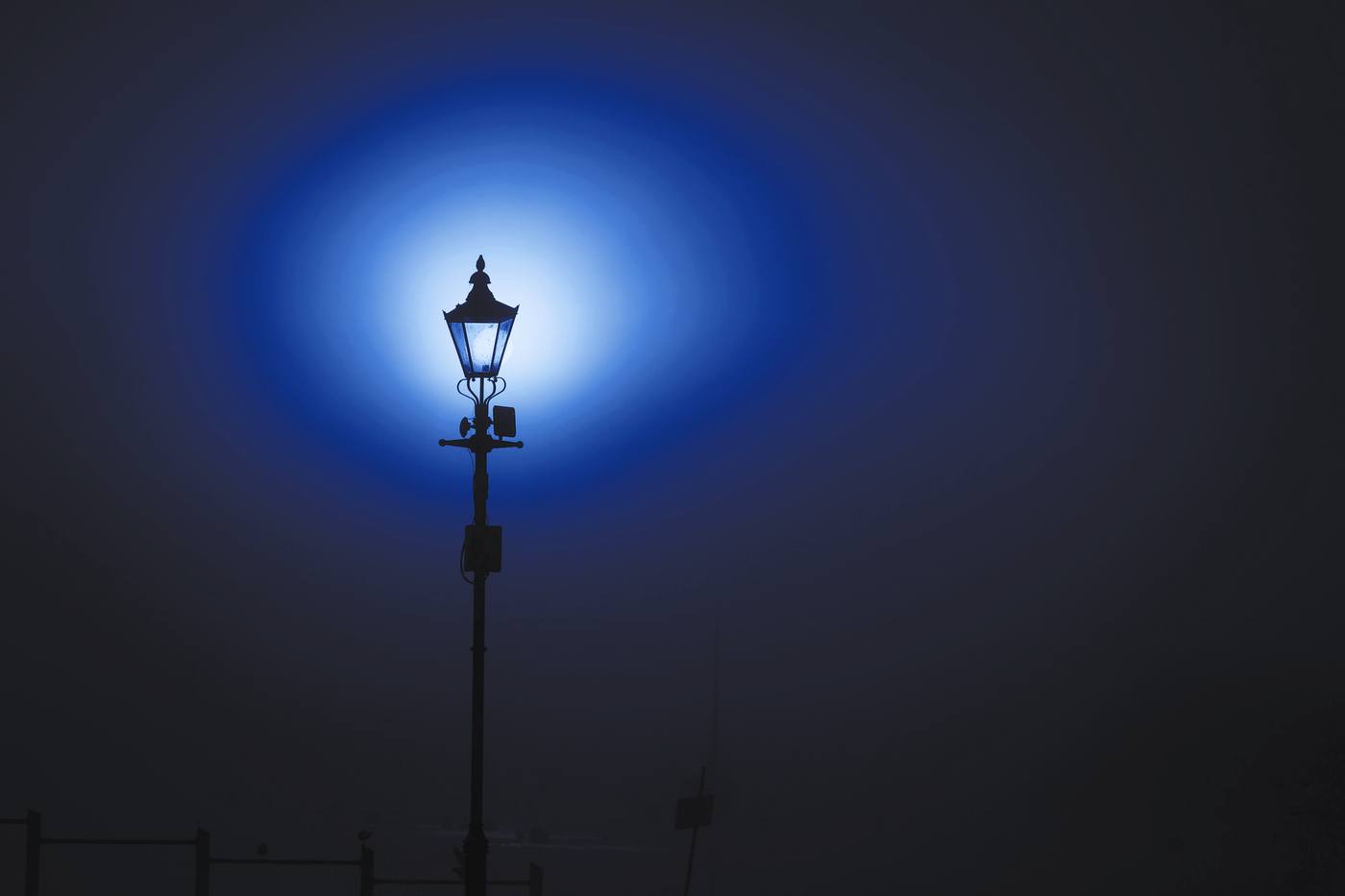Un farol antiguo rodeado de un halo de niebla, en tonos de azul