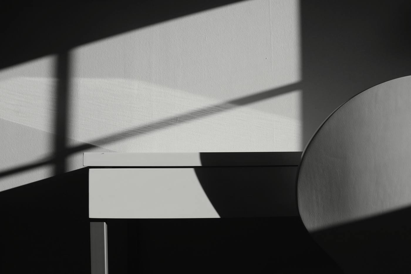 Sombras largas sobre una mesa y una pared, en blanco y negro