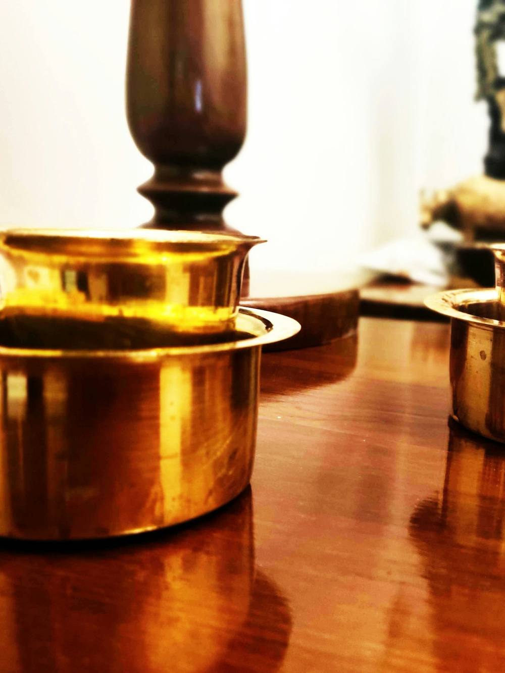 Cuencos de latón reflejados en una mesa de madera pulida