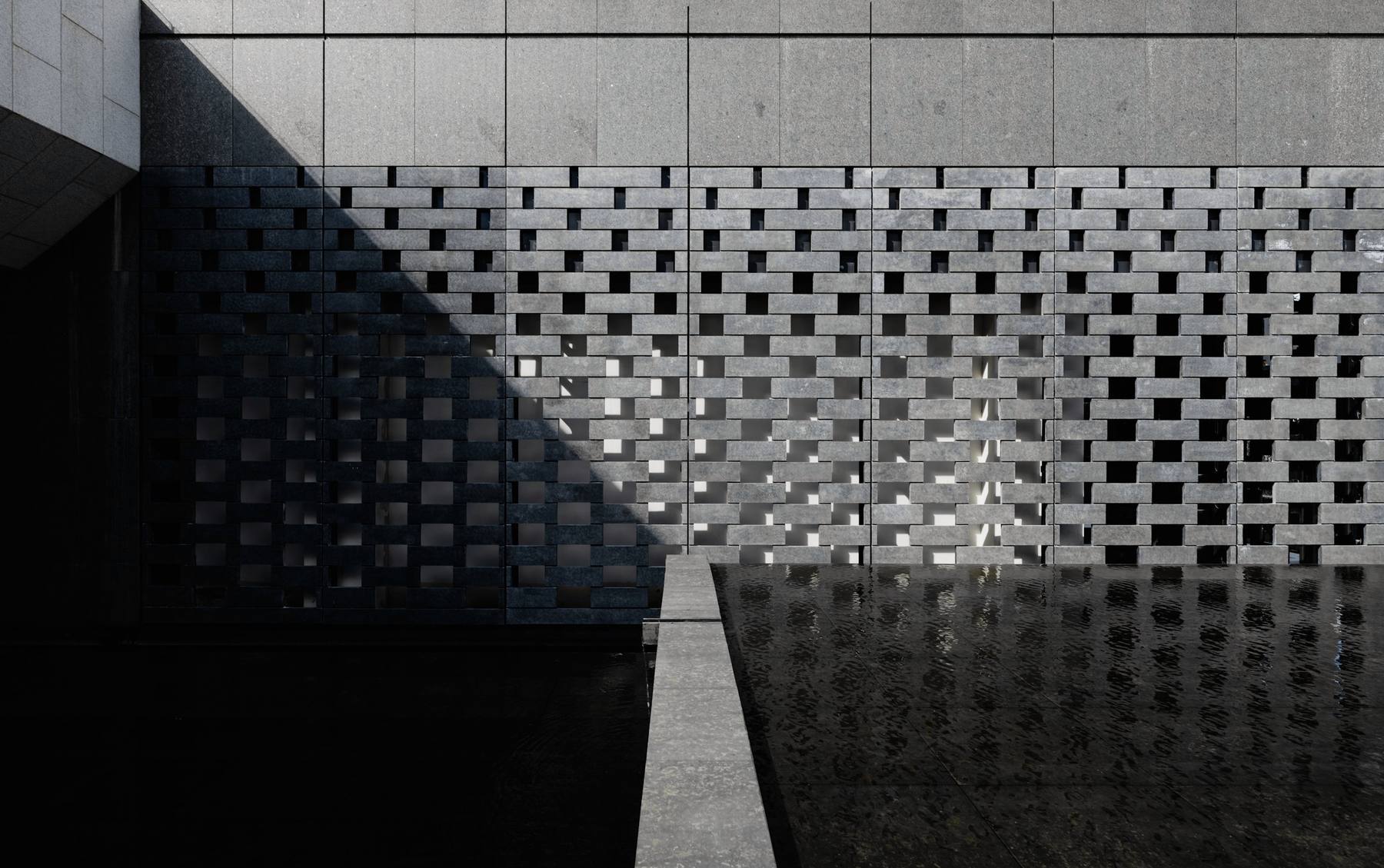 Muro de bloques calados en gris que proyecta sombras sobre un espejo de agua oscuro