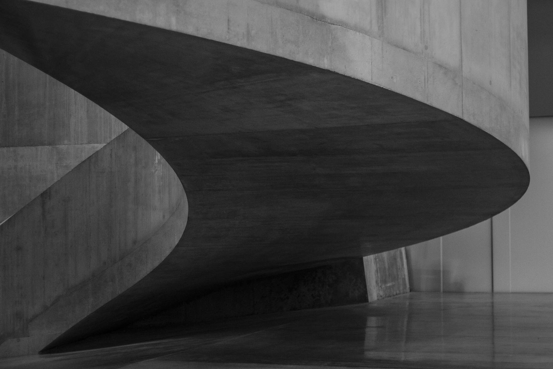 Rampa curva de hormigón en blanco y negro que gira sobre un suelo pulido