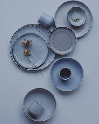 Platos y tazas de gres azul grisáceo sobre un fondo liso