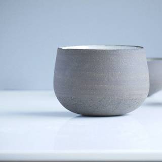 Taza ancha de gres gris sobre un fondo azul pálido