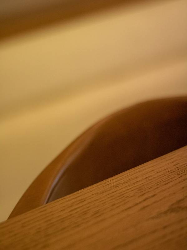 Respaldo de una silla de madera y cuero junto a una mesa