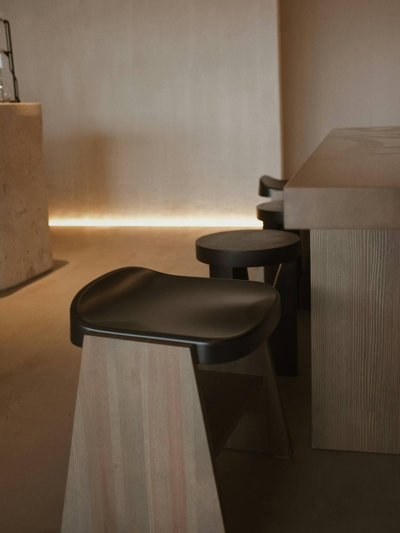 Taburete negro de barra y mostrador de madera clara en un salón cálido