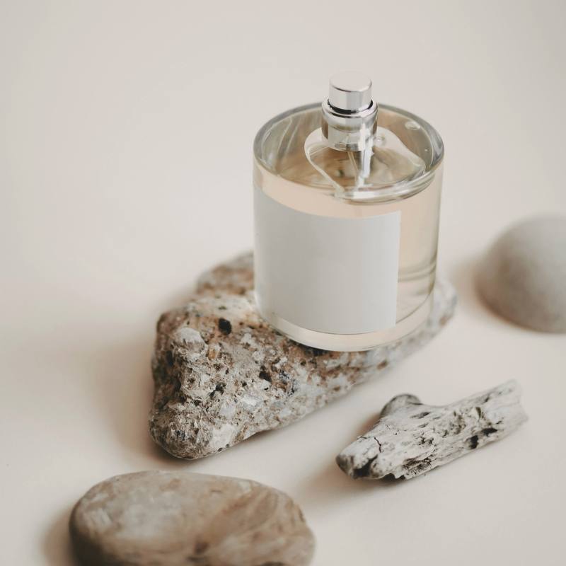 Un frasco de perfume con etiqueta en blanco sobre una roca