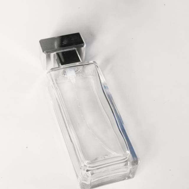 Un frasco de vidrio transparente y plano sobre una superficie blanca