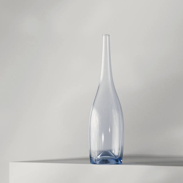 Un florero de vidrio celeste, alto y delgado, sobre un bloque blanco