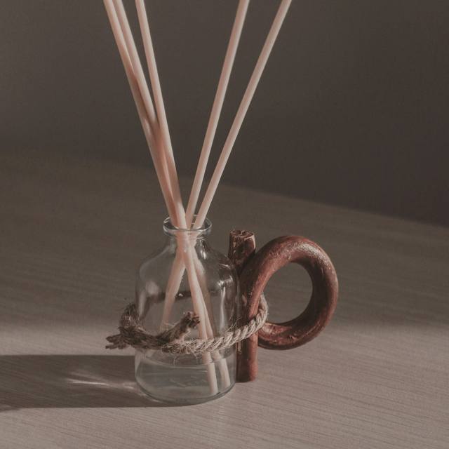 Un difusor de varillas con un frasco de vidrio y un asa de barro