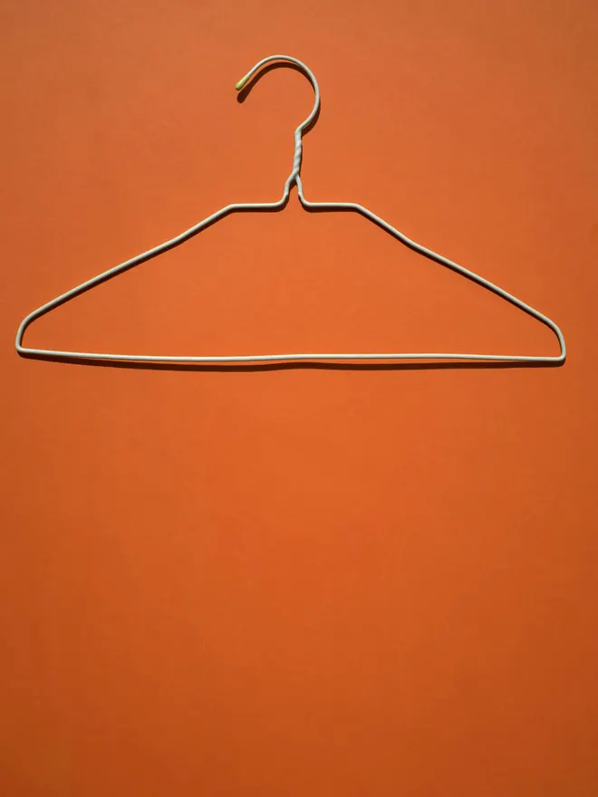 Una percha de alambre sobre un fondo naranja liso