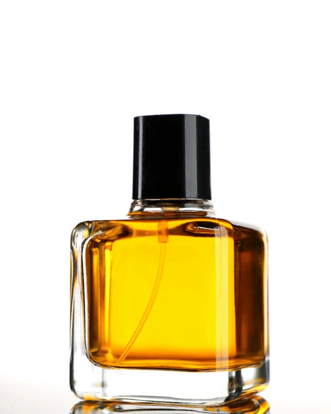 Frasco de perfume ámbar con tapa negra sobre fondo blanco