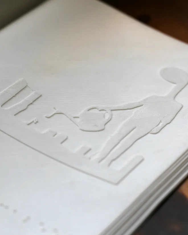 Una lámina de papel blanco con una ilustración y puntos en relieve