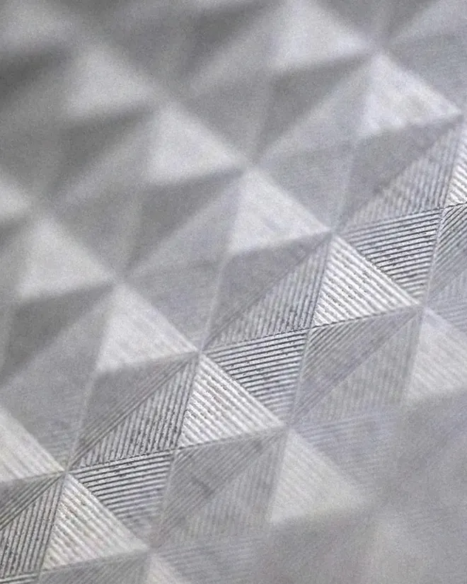 Un patrón de triángulos en relieve sobre papel plateado