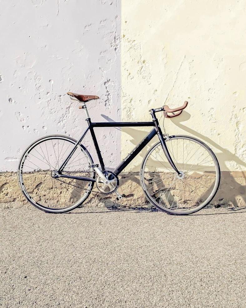 Bicicleta negra apoyada en un muro claro
