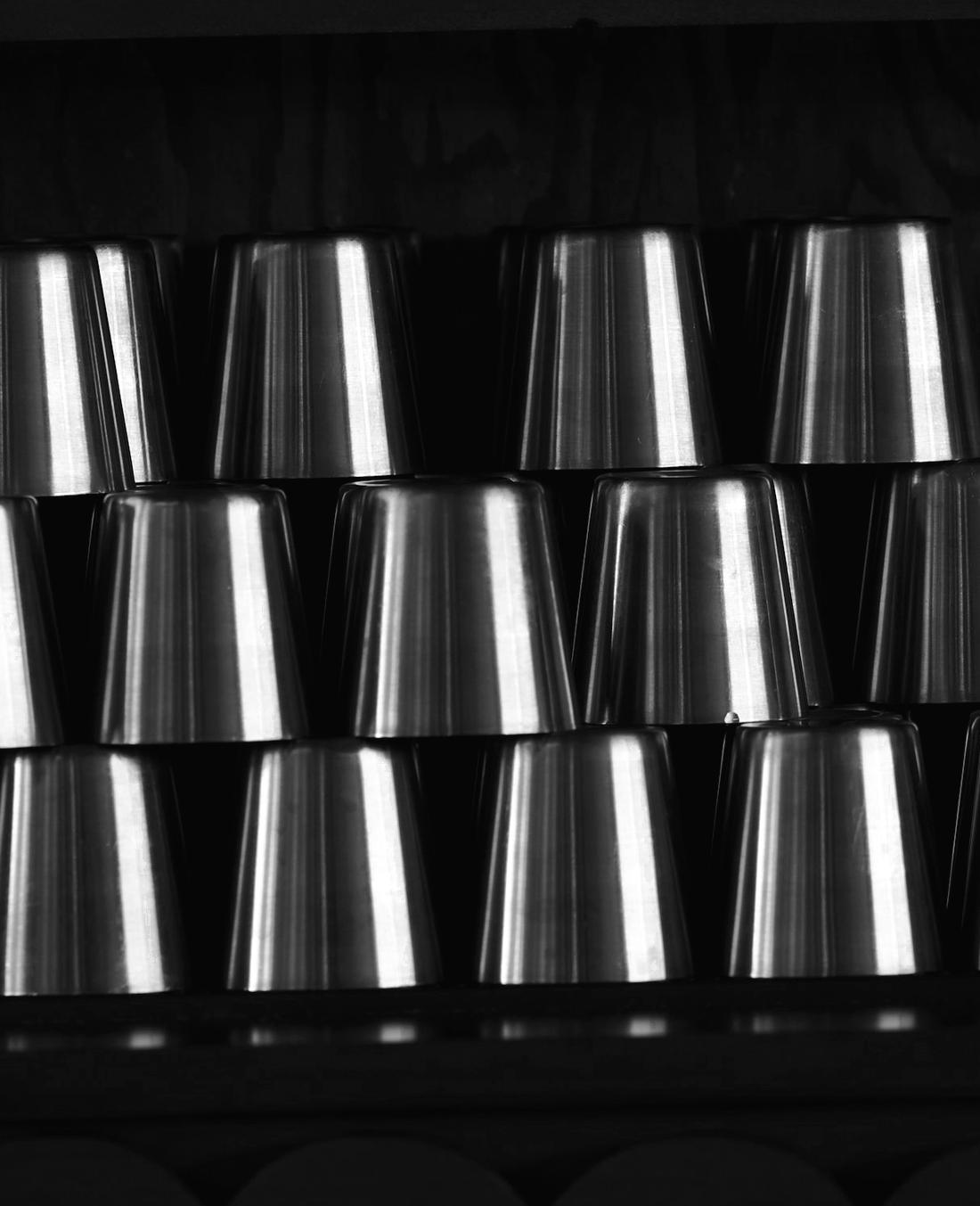 Pila de vasos de acero ordenados en un estante de madera oscura