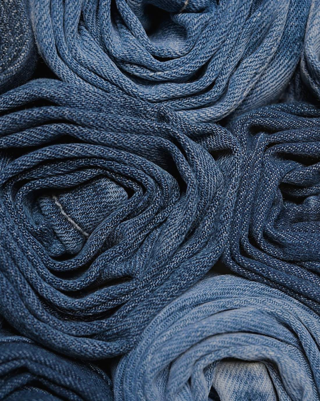 Rollos de mezclilla apilados, en azules de distintos lavados