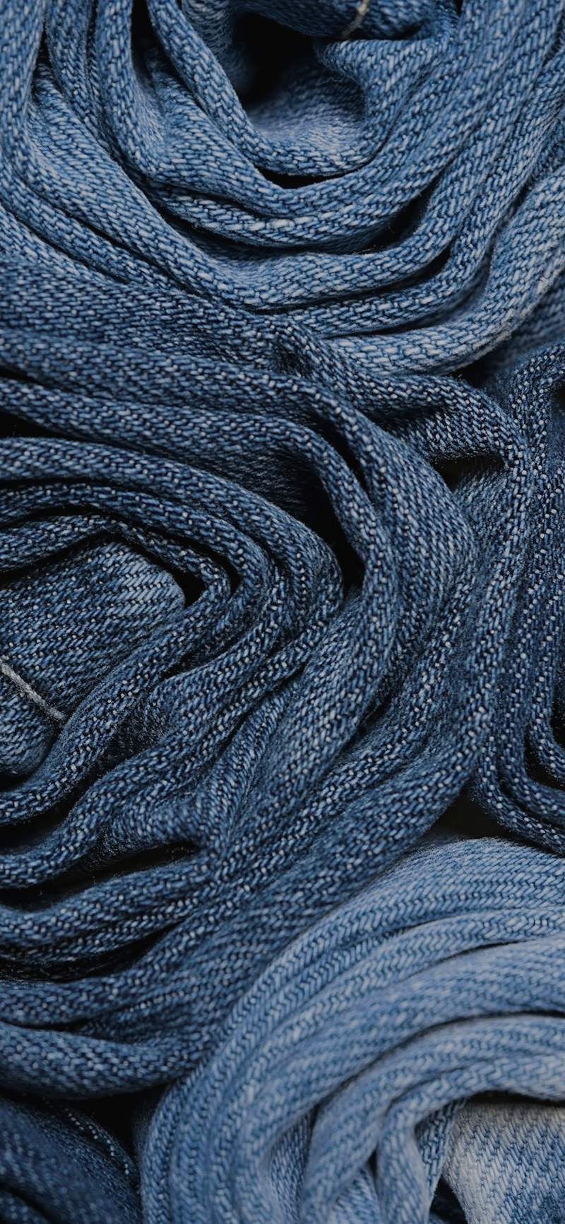 Rollos de mezclilla apilados, en azules de distintos lavados