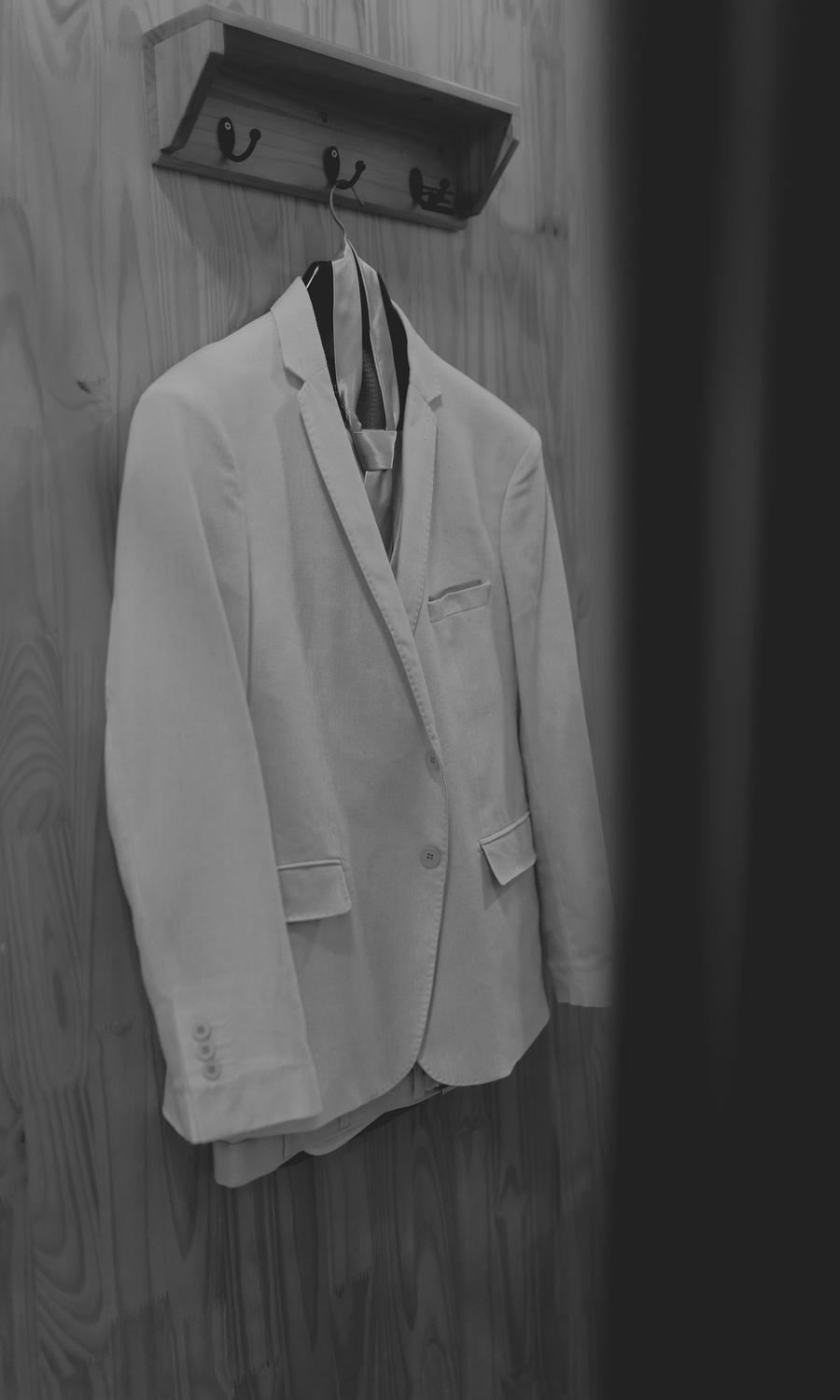 Un blazer claro colgado de un gancho en un panel de madera