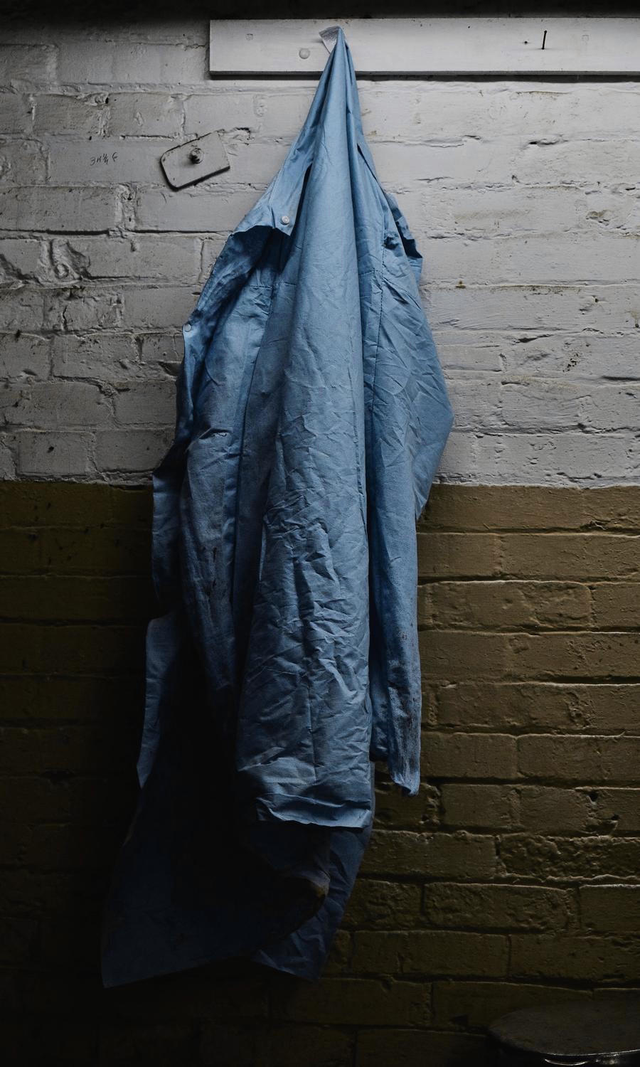 Una chaqueta larga de algodón azul colgada de un muro de ladrillo
