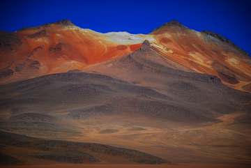 Cerro de laderas rojizas bajo un cielo azul intenso