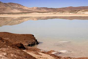 Laguna de aguas claras y orilla rojiza