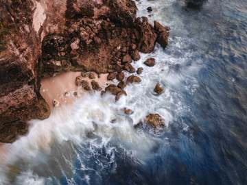 Roca rojiza batida por la espuma, vista desde arriba