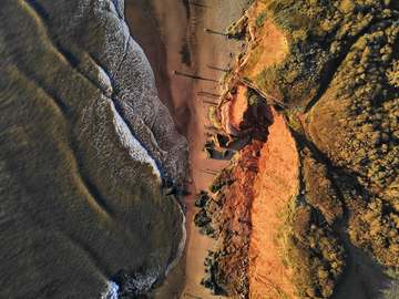 Franja de arena y barranco naranja junto al mar