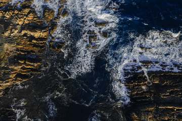 Olas rompiendo contra una costa de piedra oscura