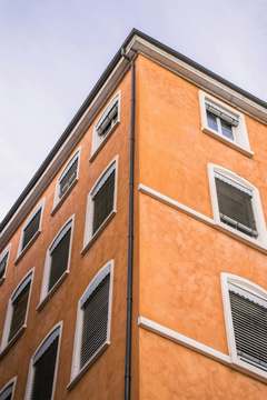 Fachada naranja vista en diagonal, con persianas oscuras