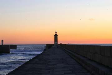 Faro al final de un malecón al atardecer