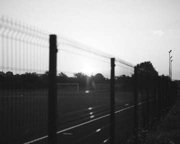 Valla de rejilla en blanco y negro con el sol detrás