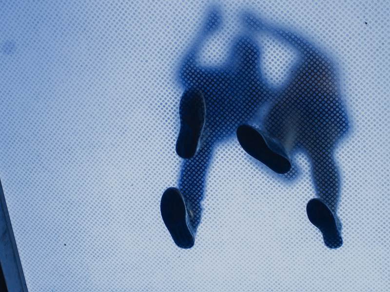 Piernas de dos personas vistas a través de un vidrio azul turquesa