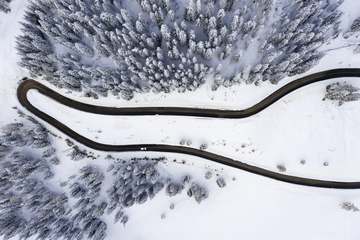 Carretera serpenteando entre pinos nevados, vista desde arriba