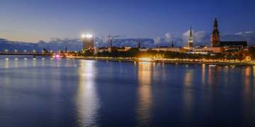 Orilla de un río con la ciudad iluminada al fondo