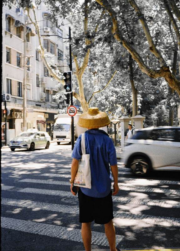Hombre con sombrero de paja cruzando la calle, de espaldas
