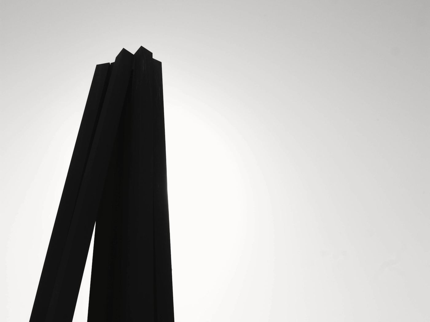 Dos columnas negras de acero a contraluz sobre un cielo blanco