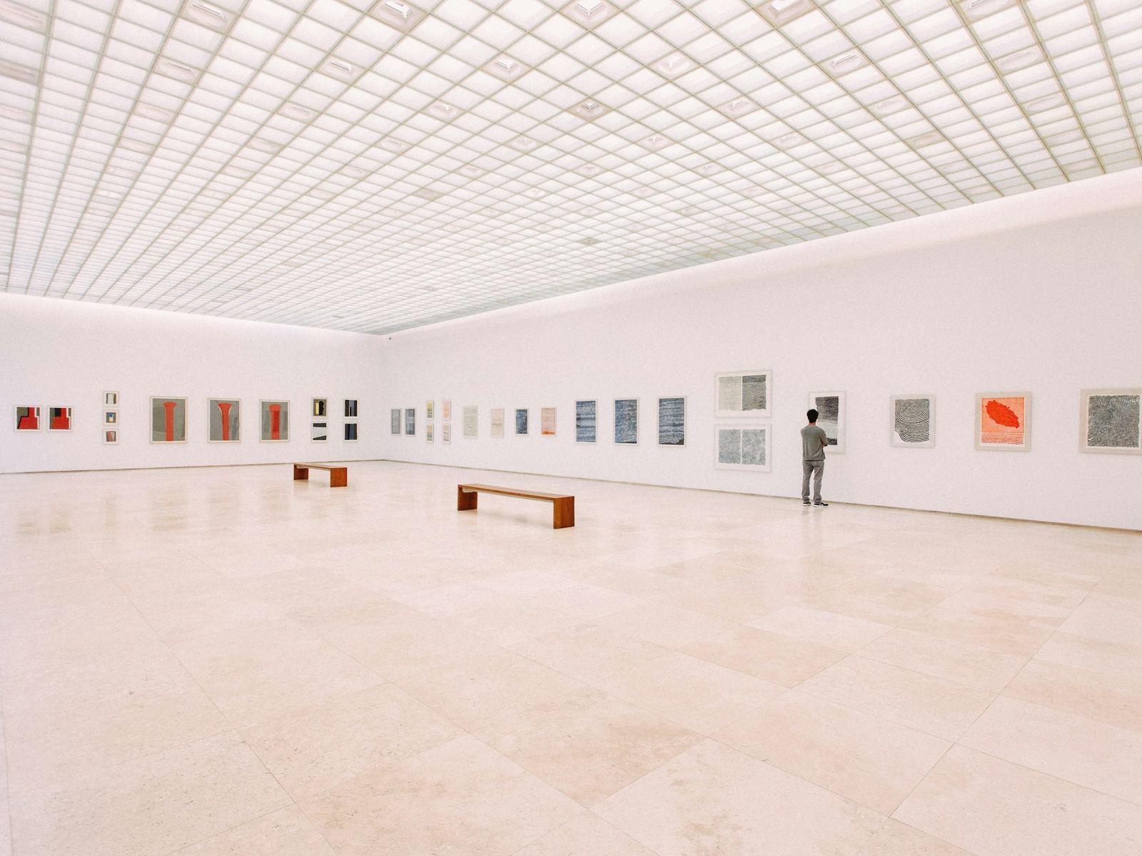 Sala de muros grises con fotografías enmarcadas iluminadas con foco y su reflejo sobre el suelo pulido