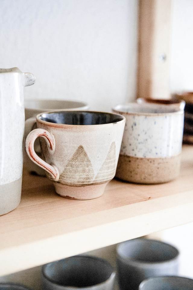 Tazas de cerámica con trazos geométricos sobre una repisa de madera clara