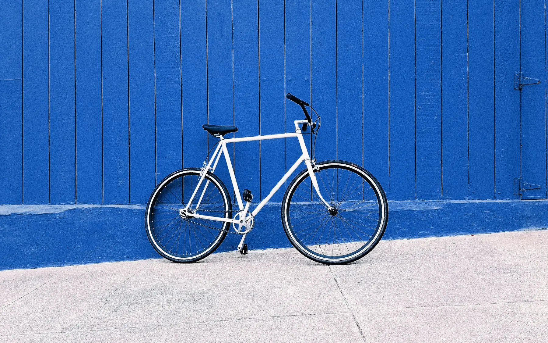 Bicicleta blanca apoyada en una pared turquesa