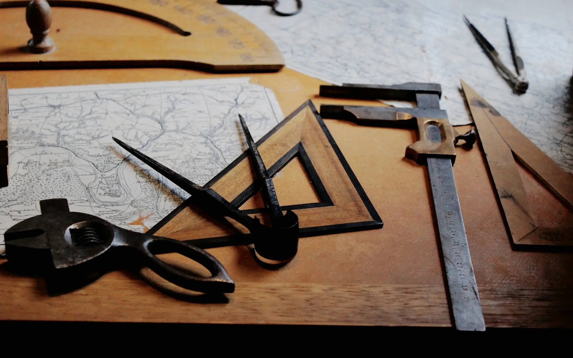 Escuadras, compás y reglas de dibujo sobre una mesa de madera