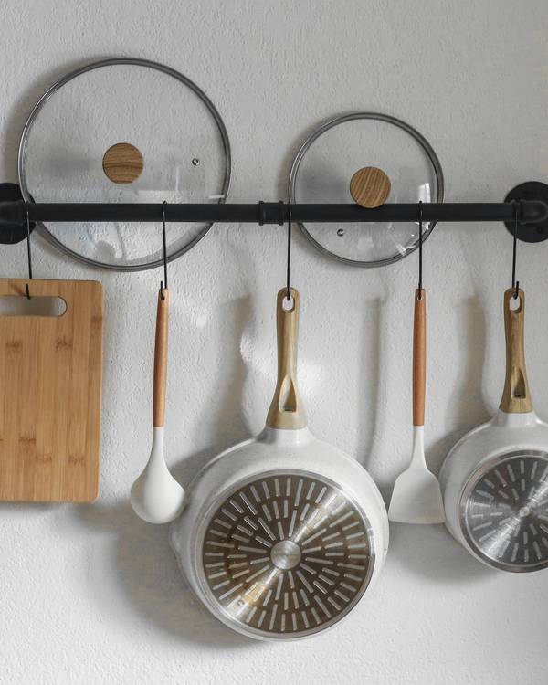 Una barra en la pared con tapas y sartenes colgadas