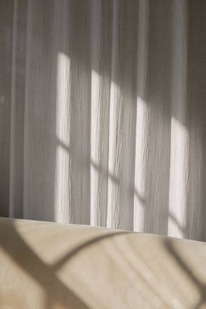 Cortinas claras con franjas de luz sobre el suelo