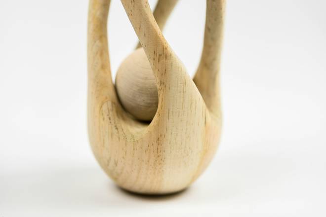 Escultura de madera clara que abraza una esfera