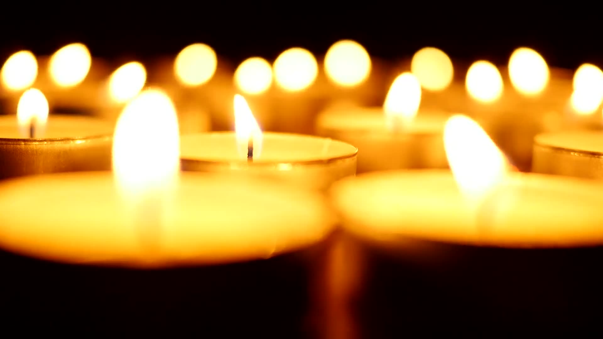 Hileras de velas encendidas con un resplandor dorado