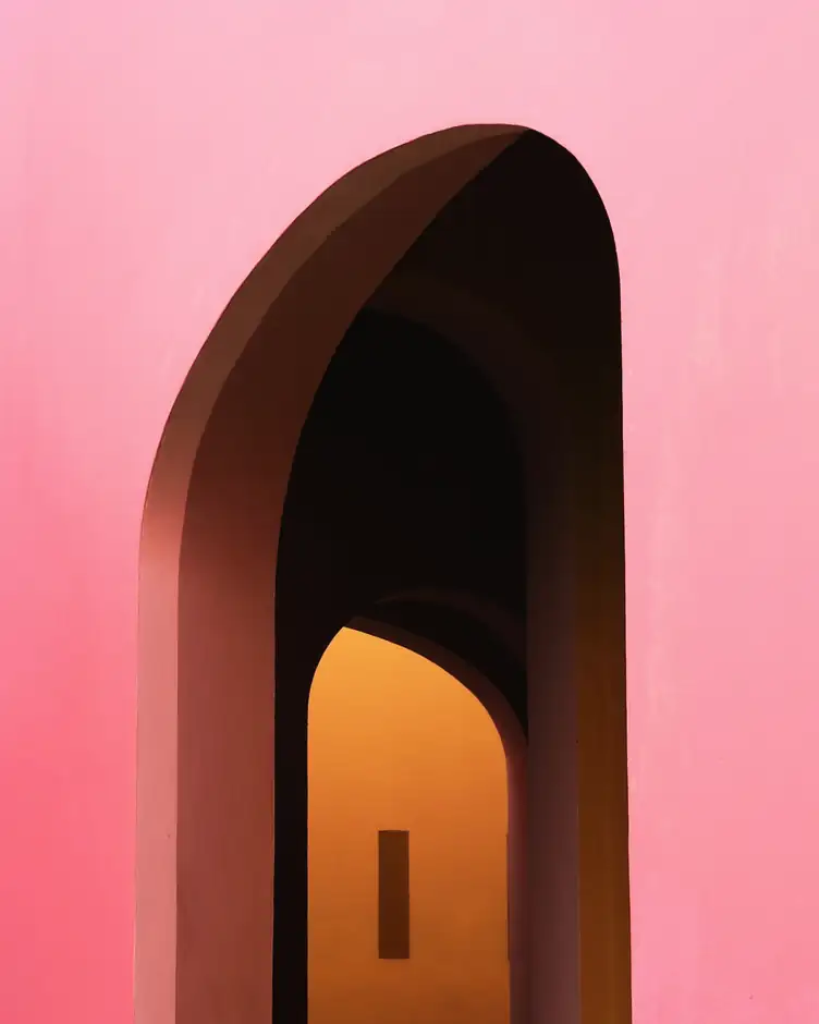 Arco oscuro en un muro rosa, con luz cálida al fondo